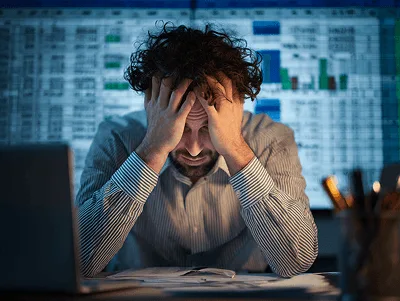 A construction professional overwhelmed by financial data, sitting in front of spreadsheets with his head in his hands — Boosting Mental Health in the Construction Industry A Comprehensive Guide article