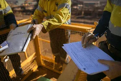 How to Deliver Accurate Construction Estimates? 2 Workers in safety gear fill out and exchange documents at a construction site — How to Deliver Accurate Construction Estimates article