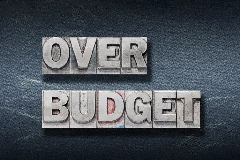 The words “OVER BUDGET” displayed in bold metal letterpress type — Why Do Construction Projects Go Over Budget article